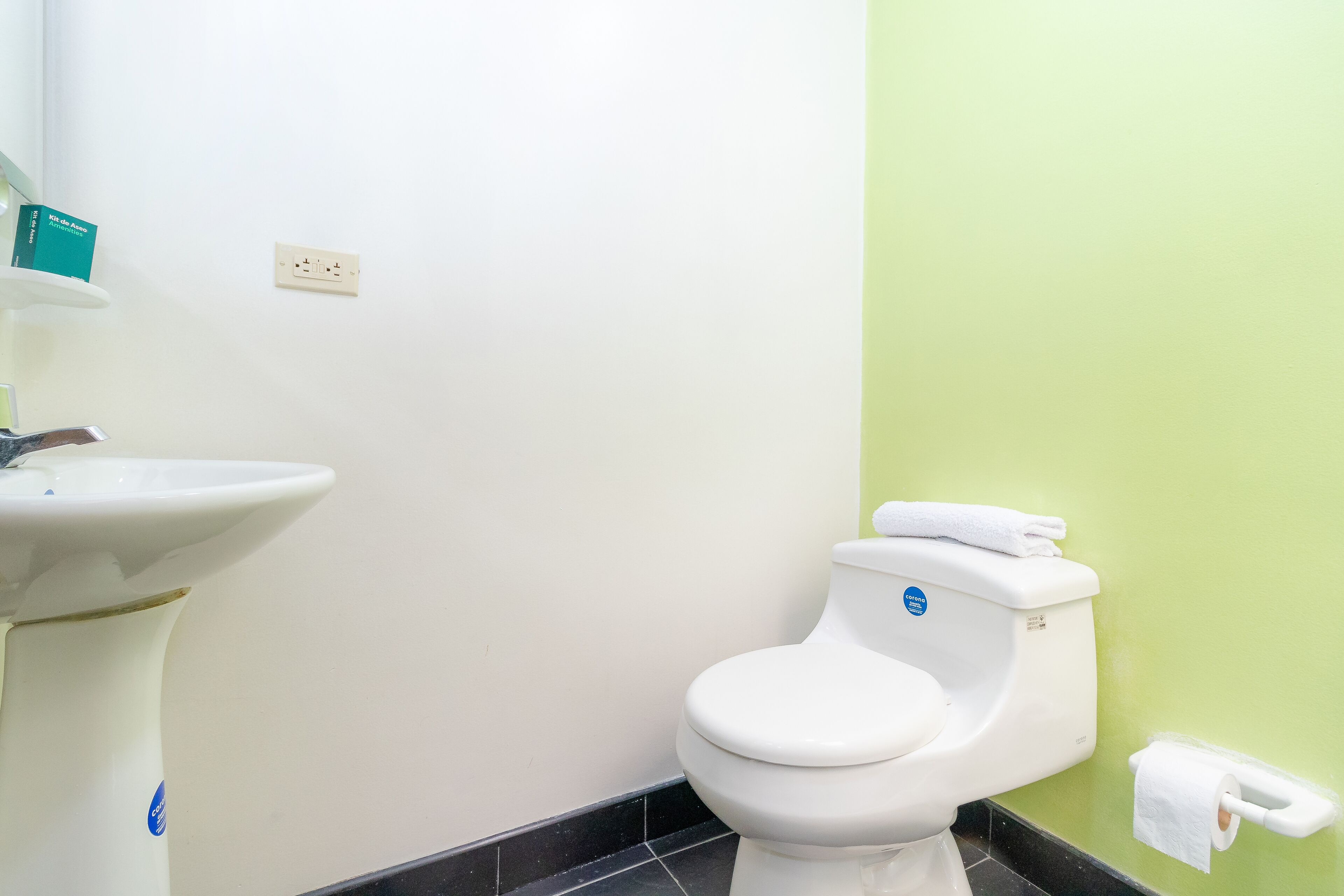 A bathroom with a white sink, a toilet, and a green wall.