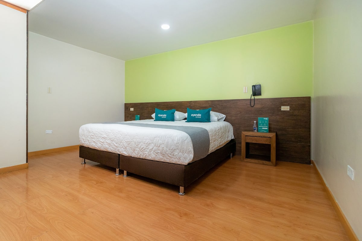 A bedroom with a bed, a nightstand, and a phone.