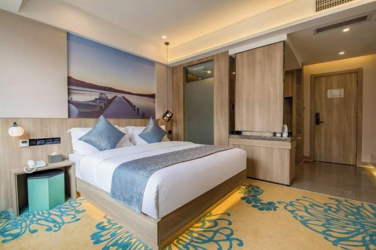 Una habitación de hotel con una cama, un escritorio, un espejo y un cuadro en la pared.