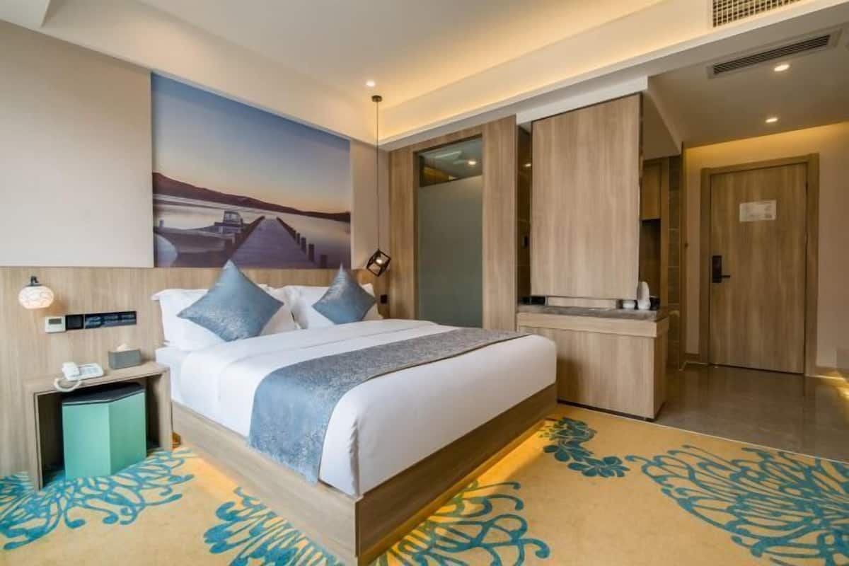 Una habitación de hotel moderna con una cama grande, un escritorio y un cuadro en la pared.