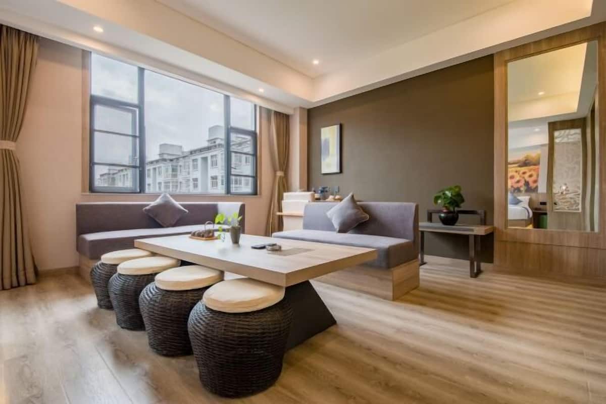Una sala de estar moderna con un sofá, una mesa de centro y vistas a edificios a través de amplios ventanales.