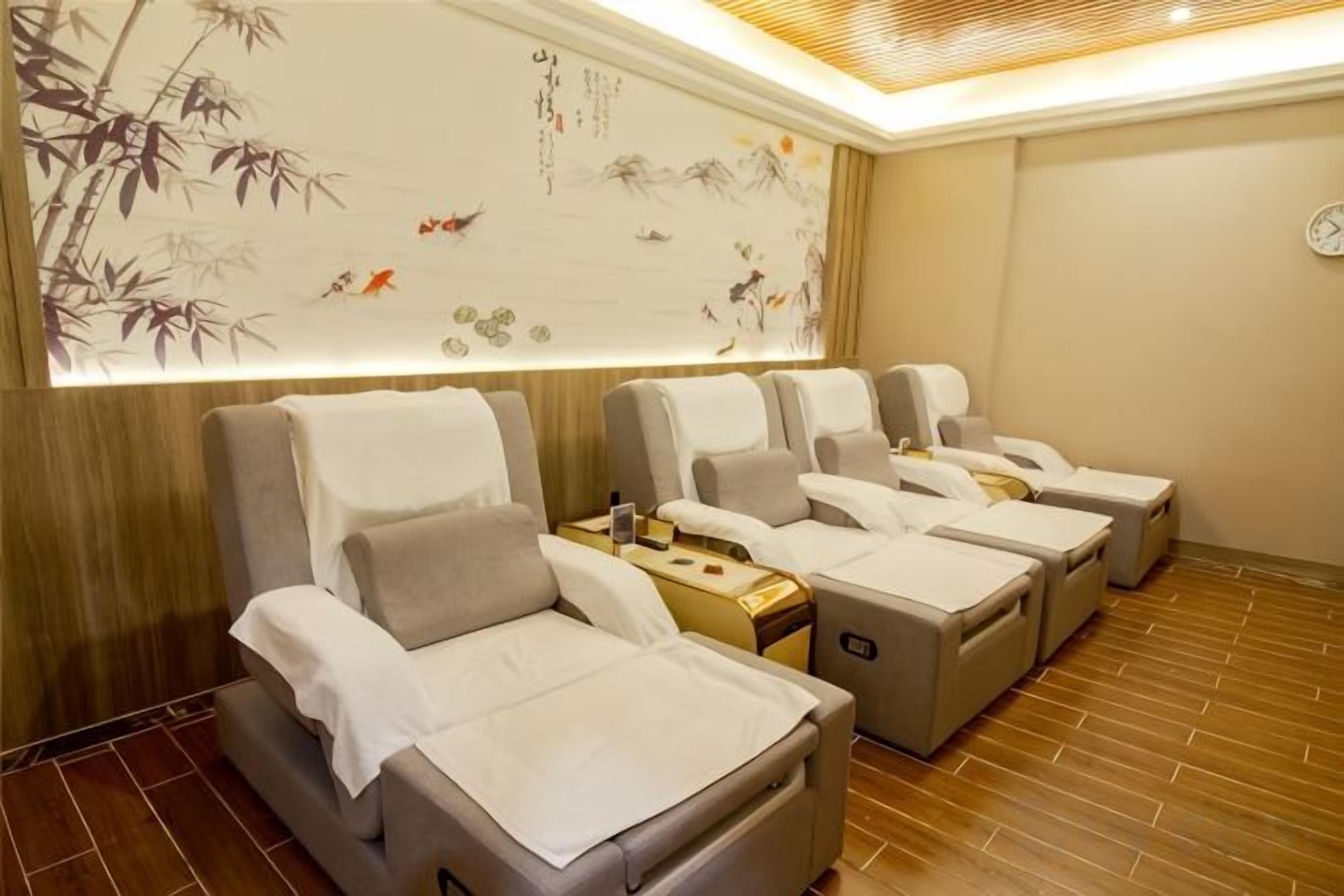 Ein Raum mit Massagesesseln, einem an der Wand befestigten Massagestuhl und einem Holzboden.