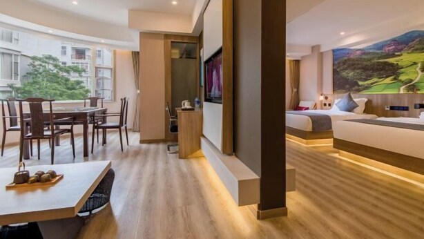 A modern hotel room with a dining area, a large bed, and a scenic painting on the wall. - Manya Hotel (Xinping)