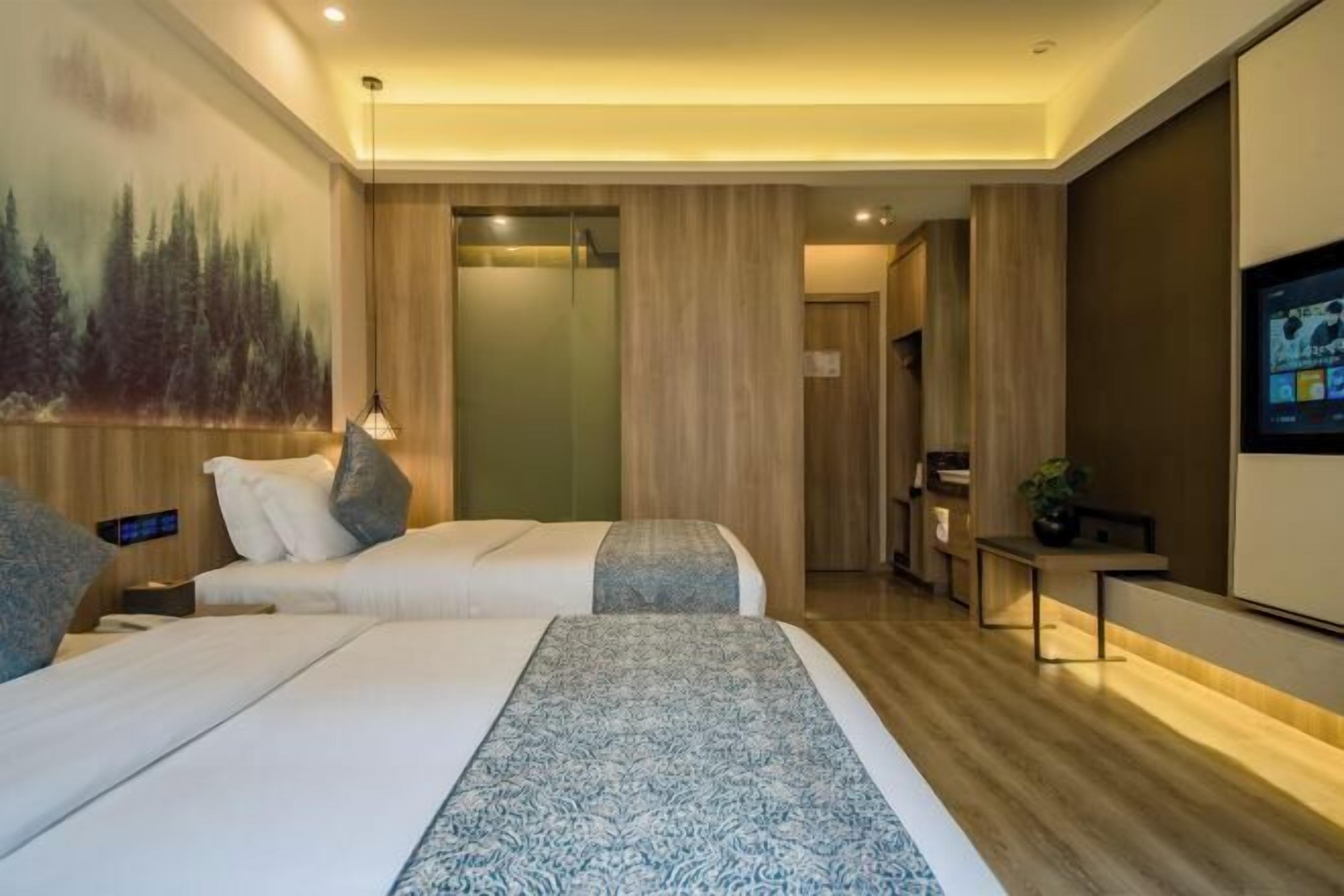 Une chambre d’hôtel moderne avec deux lits, un petit bureau, une télévision et une fresque murale.