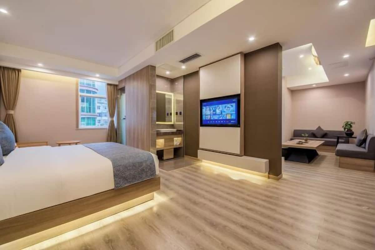 Una habitación de hotel moderna con una cama, un televisor, un sofá y una mesita.