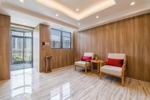 A modern interior with a glass door leading to a balcony, two wooden chairs with cushions, and a polished marble floor.