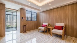 A modern hotel room with a marble floor, two wooden chairs with cushions, a small table, and a window with a city view. - Manya Hotel (Xinping)