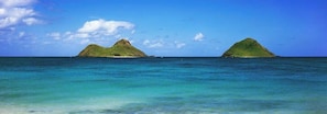 A clear view of two green islands in the ocean with calm waters.