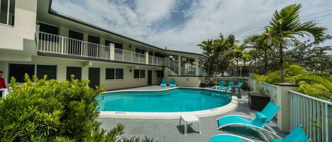 Een buitenzwembad, parasols voor strand/zwembad