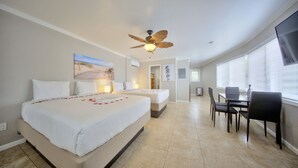 A hotel room with a large bed, a ceiling fan, a dining area with chairs and a table, and a TV mounted on the wall. - Surf and Sand Seaside (Pompano Beach)
