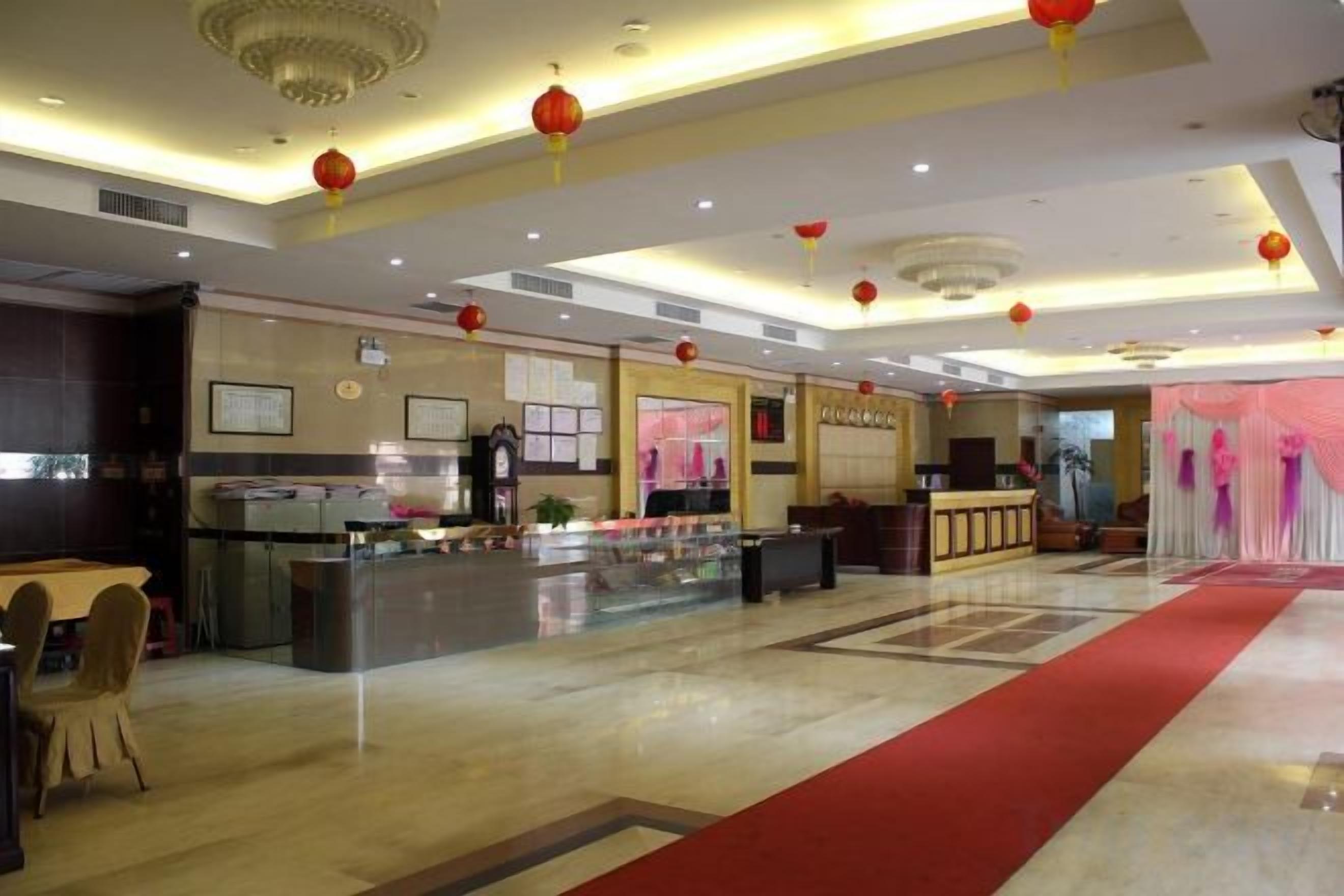 Eine Hotelhalle mit einer Rezeption, einer Theke mit Speisenauslage und einem roten Teppich.
