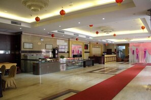 A hotel lobby with a reception desk, a counter with food display, and a red carpet. - Foshan Tenghai Hotel (Foshan)