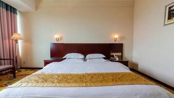 Habitación de hotel con una cama grande, dos mesitas de noche, un cabecero y dos lámparas fijadas a la pared.
