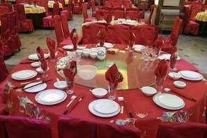 A round table with red tablecloths, white plates, and clear glassware.