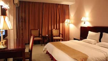 Habitación de hotel con cama, dos sillas, un escritorio y lámparas.