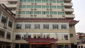 A multi-story hotel with balconies, a traditional entrance, and a signboard.