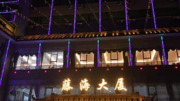 Un edificio con letreros iluminados y un balcón.