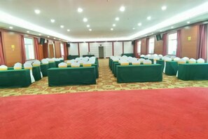 Un salón de conferencias con varias mesas, alfombra roja y un suelo con estampado.