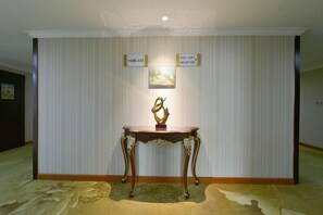 Ein Empfangsbereich mit einer Rezeption, einem gerahmten Bild und einer Wand mit zwei Schildern.