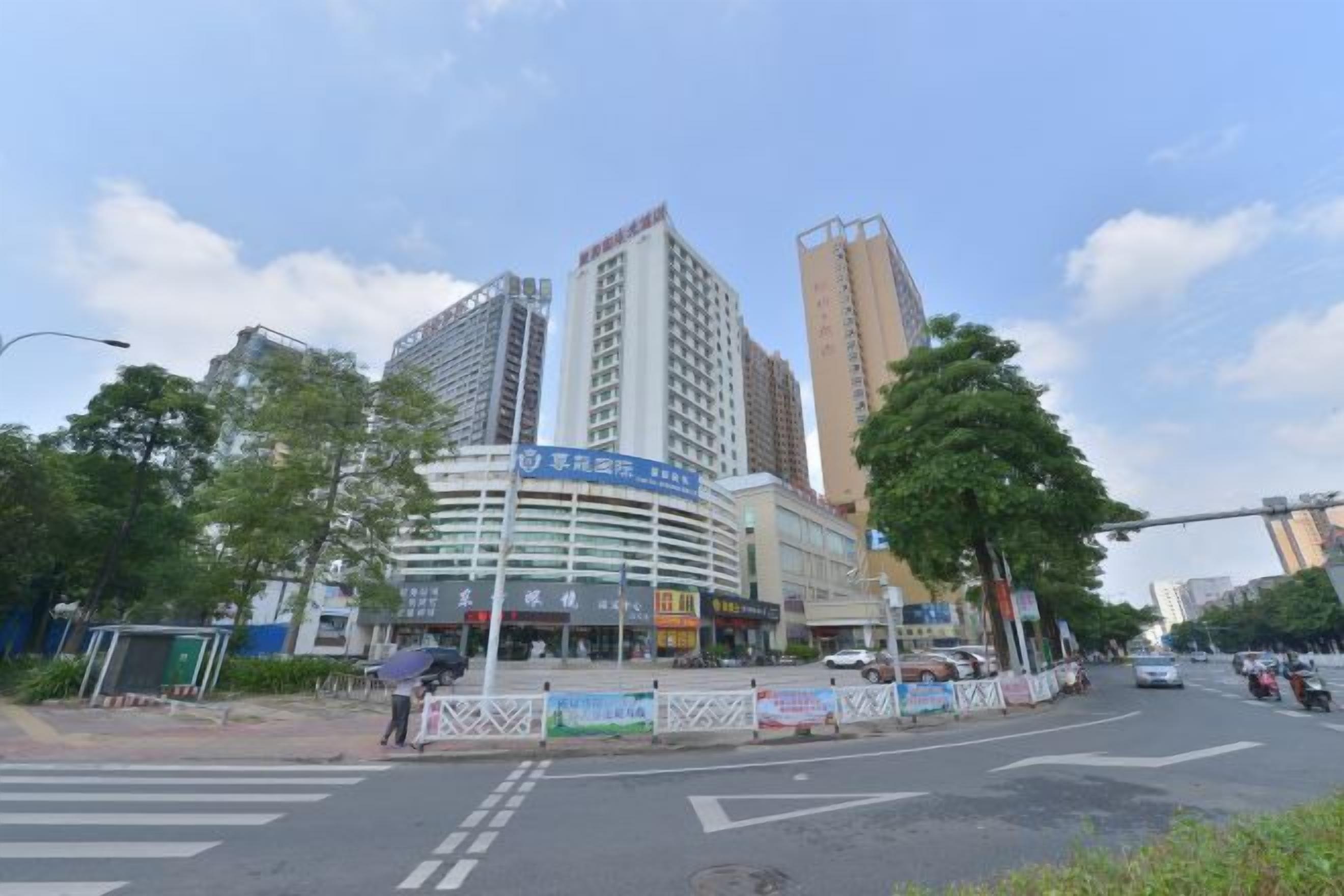 A multi-story building with a curved facade, a signboard, and a pedestrian crossing.