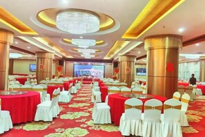 A banquet hall with round tables, white chairs, and a red carpet. - Junmei International Hotel (Guigang)