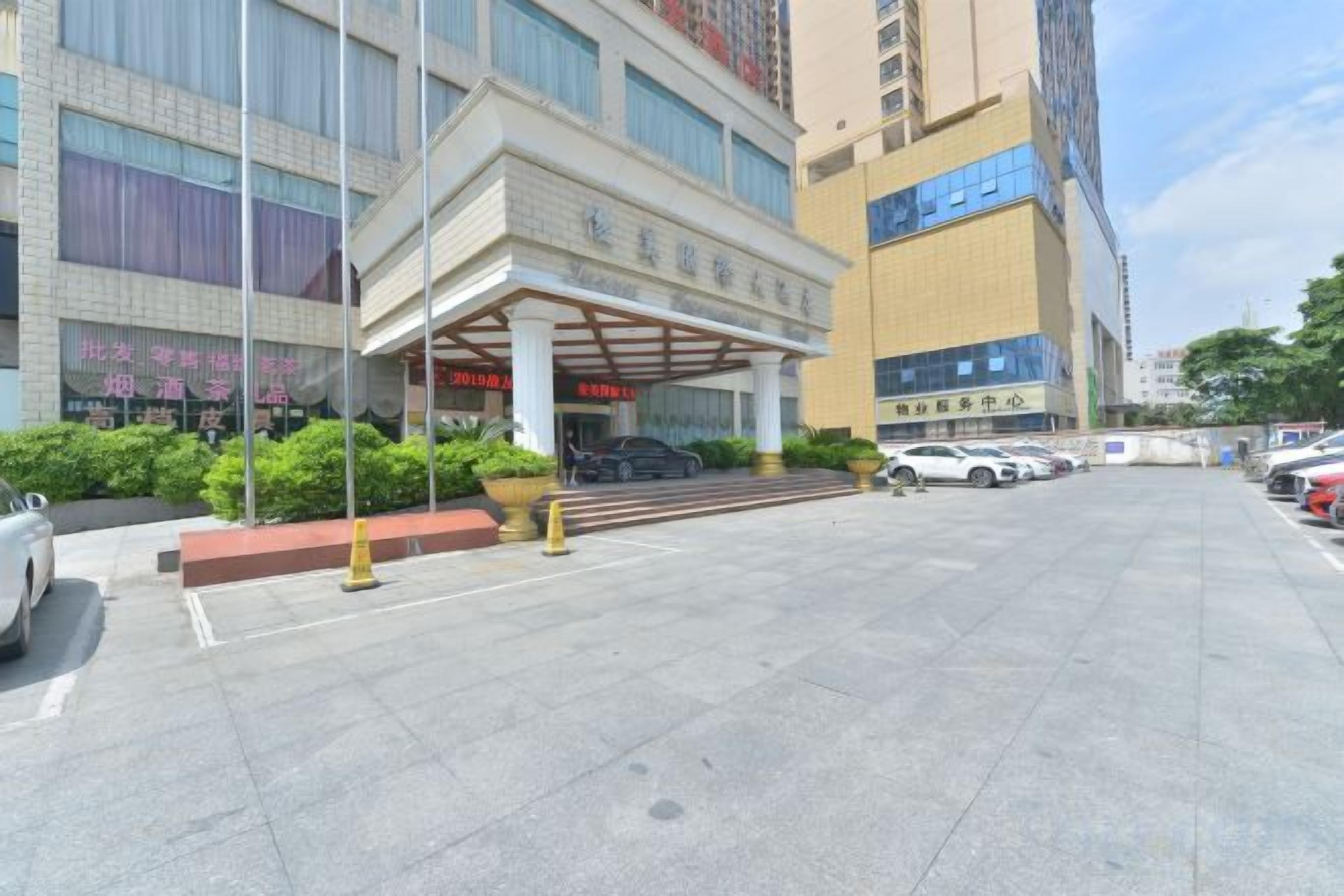 Entrada de hotel con zona cubierta, estacionamiento y un edificio de varios pisos.