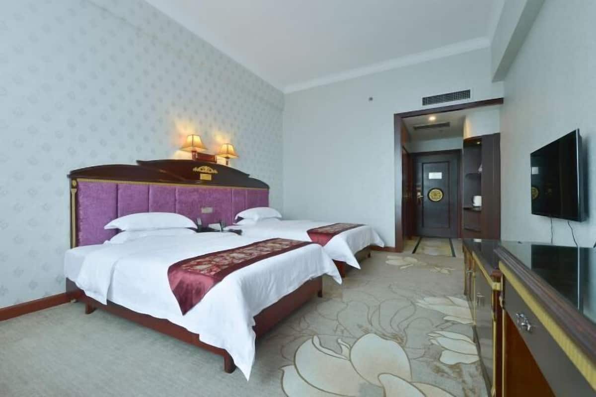 A hotel room with two beds, a TV, and a door leading to a bathroom.