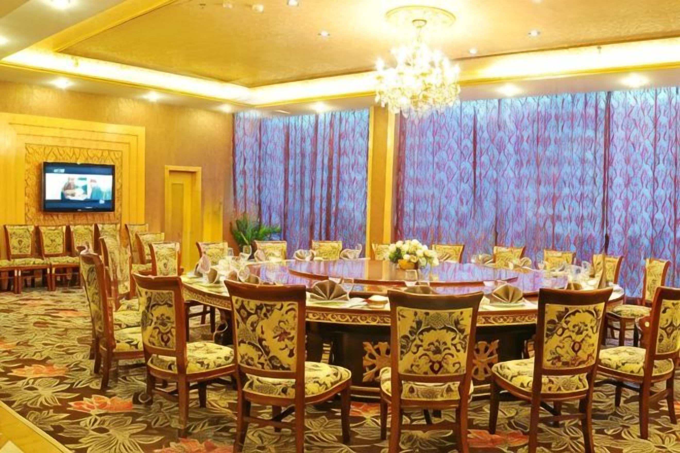 A conference room with a large oval table, multiple chairs, a television, and a patterned carpet.