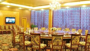 A conference room with a large oval table, multiple chairs, a television, and a patterned carpet.