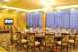 A conference room with a large oval table, multiple chairs, a television, and a patterned carpet.