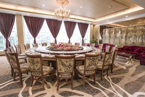 Un comedor con una mesa redonda, sillas y una araña.
