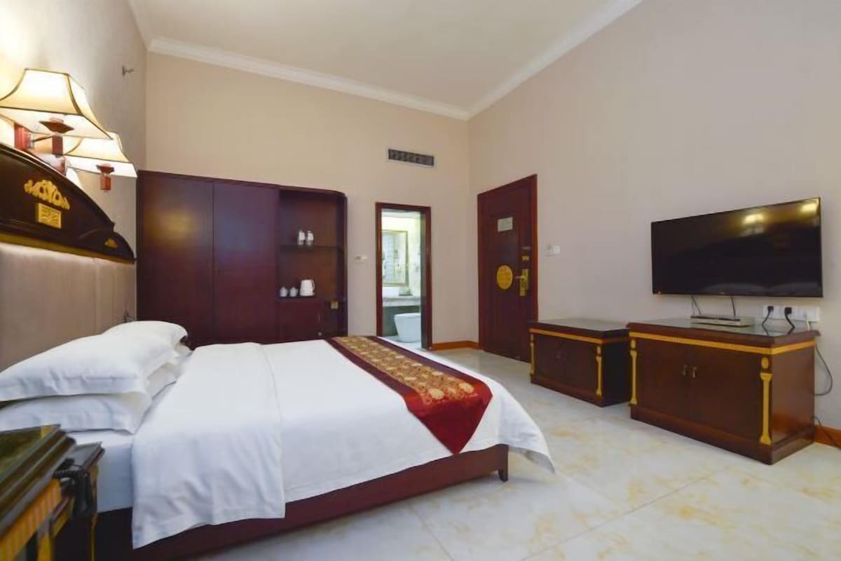 Une chambre d’hôtel avec un grand lit, une télévision, une armoire et une porte de salle de bain.