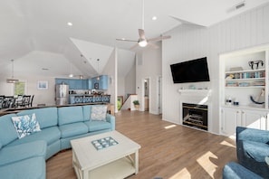 A spacious living area with a sectional sofa, a coffee table, a fireplace, and a television mounted on the wall. - Sea Haven- Heated Salt Water Pool | Sleeps 16 | Dogs OK |500ft to beach |Hot Tub (Corolla)
