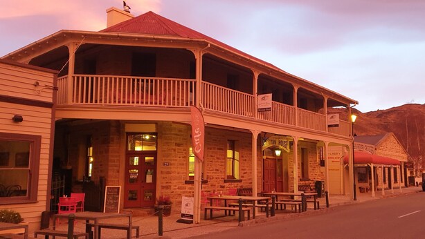 A two-story building with a balcony, multiple windows, and outdoor seating. - Dunstan House (Clyde)