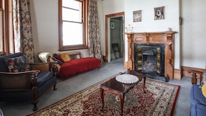 A traditional living room with a fireplace, wooden furniture, and a patterned rug. - Dunstan House (Clyde)