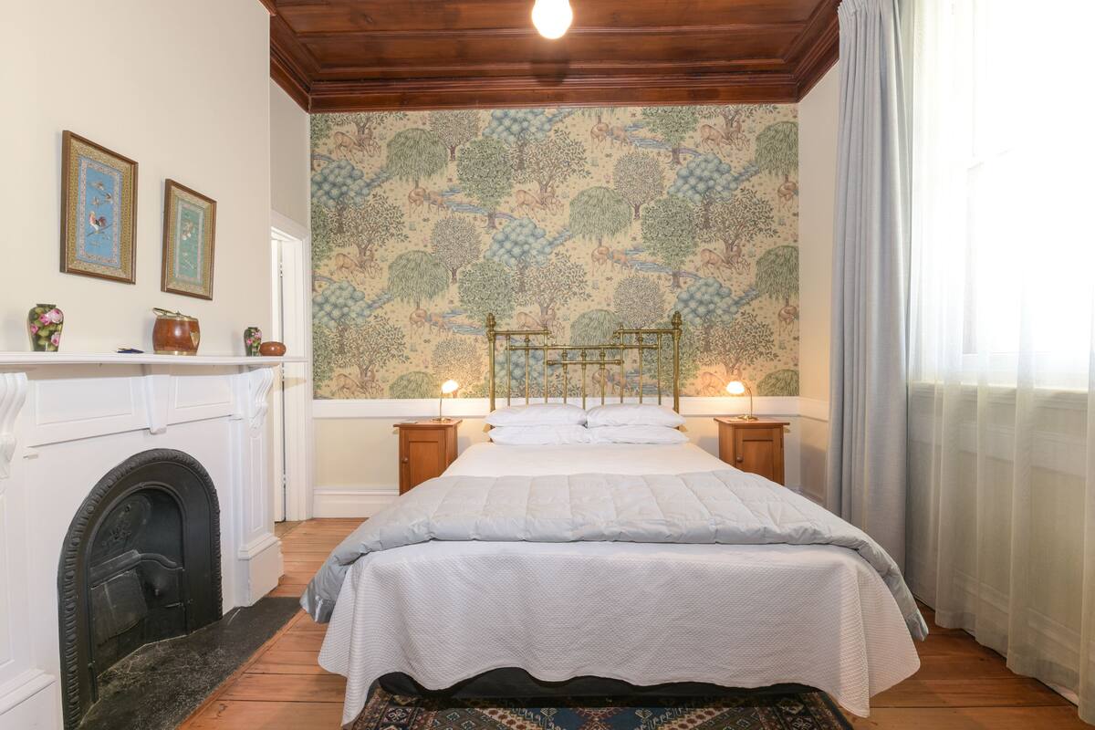 A bedroom with a large bed, a fireplace, and a mural on the wall.