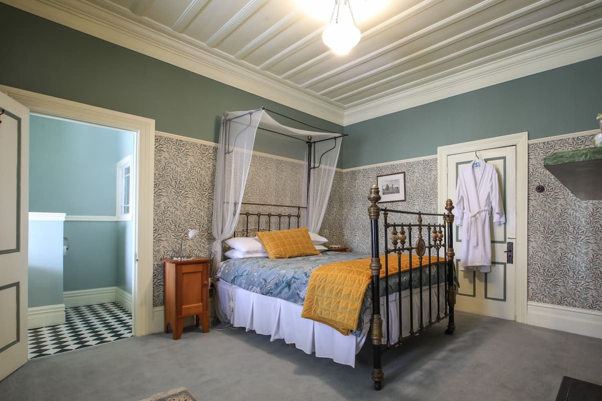 A bedroom with a four-poster bed, a canopy, a bedside table, and a nightstand.