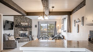 A kitchen with a stone wall, a fireplace, and a dining area with chairs.