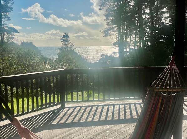 Um deck de madeira com uma rede e vista para o oceano.