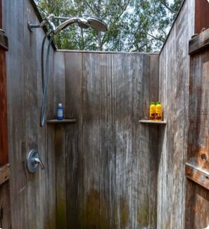 Eine Duschrückwand aus Holz mit einer Regendusche und zwei Ablagen für Flaschen.