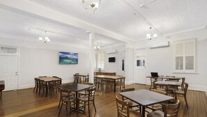 A spacious dining area with wooden tables and chairs, white walls, and a ceiling with exposed beams. - Central Hotel Stroud (Stroud)