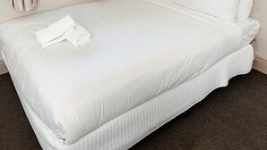 A neatly made bed with white linens, a window with curtains, and a plain wall. - Central Hotel Stroud (Stroud)