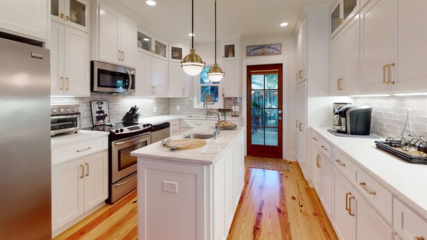 Una cocina moderna con armarios blancos, electrodomésticos de acero inoxidable y una isla central.