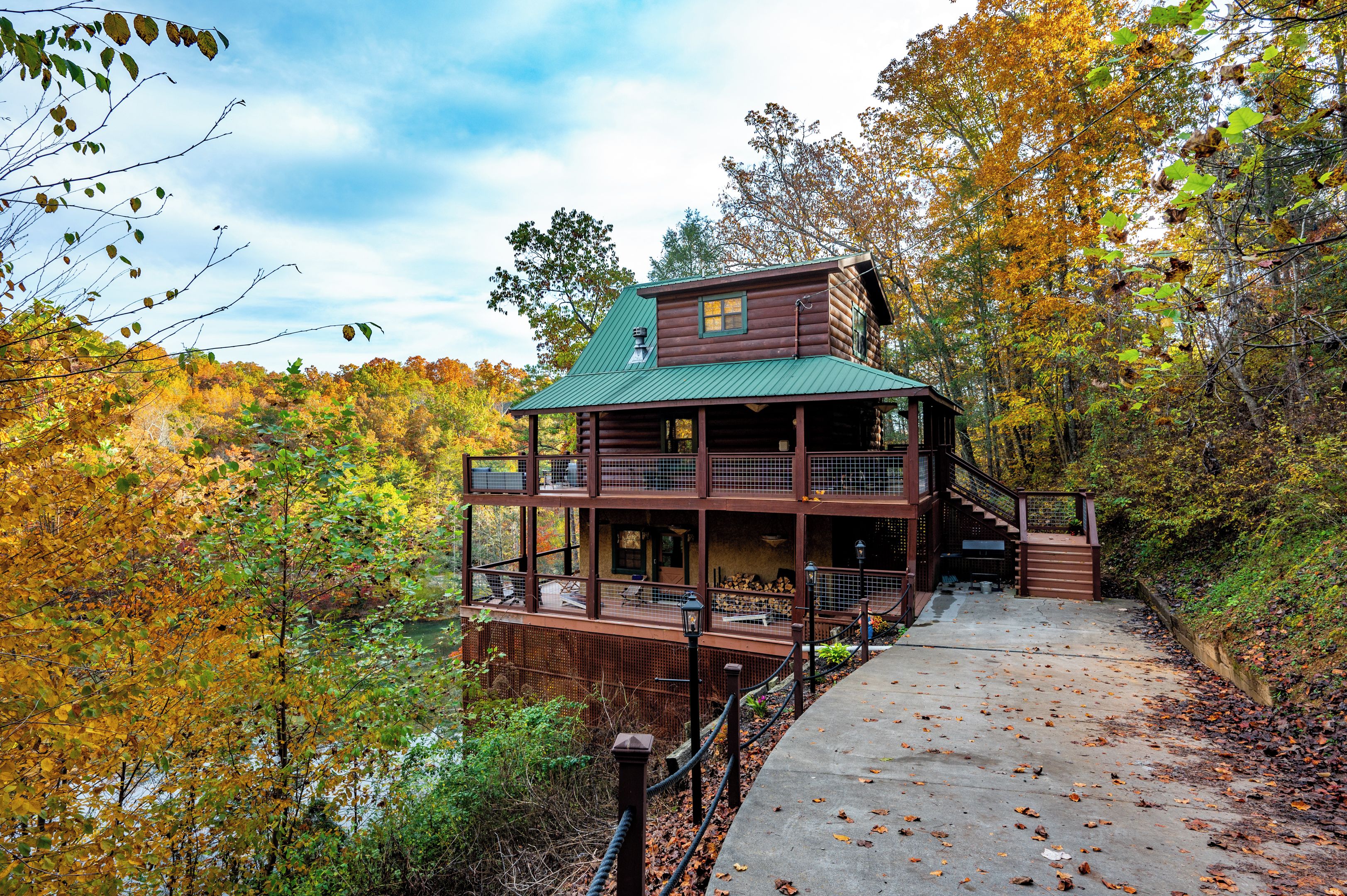 A log cabin with a green roof, a balcony, and a deck.