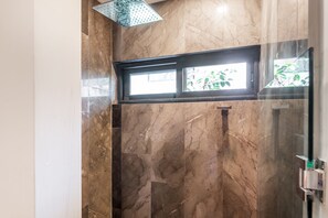Une salle de bain avec un mur en marbre, une fenêtre et un espace douche.