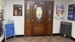 A wooden door with glass panels, flanked by various posters advertising local events and products. - Studio 6 Extended Stay - Savannah, GA - Gateway & I-95 (Savannah)