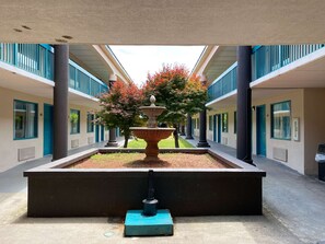 A courtyard with a central fountain, surrounded by columns and a row of doors.