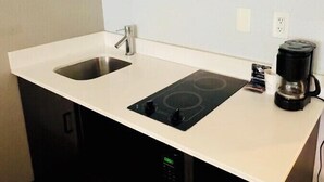 A compact kitchen with a double sink, a stovetop, and a coffee maker. - Studio 6 Extended Stay - Savannah, GA - Gateway & I-95 (Savannah)
