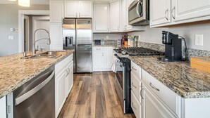 Eine moderne Küche mit weißen Schränken, Edelstahlgeräten, Granit Arbeitsplatten und einem eingebauten Backofen.