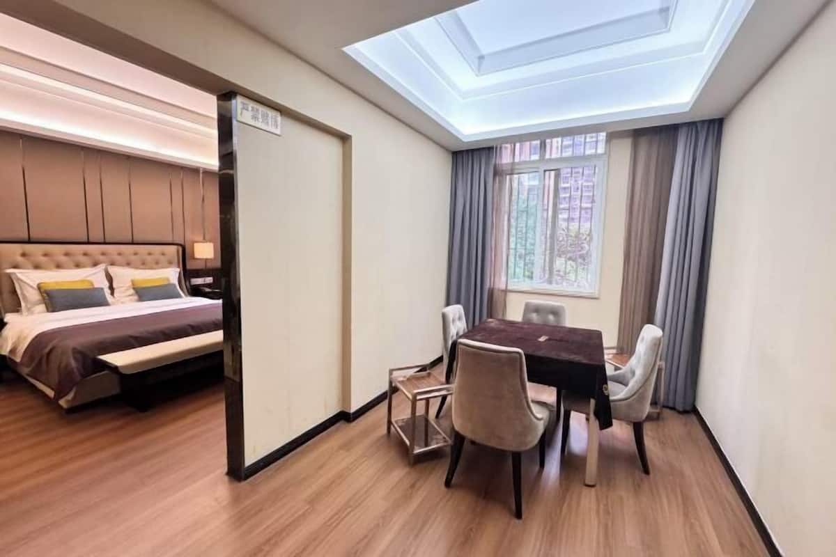 Una habitación de hotel con cama, una mesa de comedor y sillas, un tragaluz y una ventana con cortinas.
